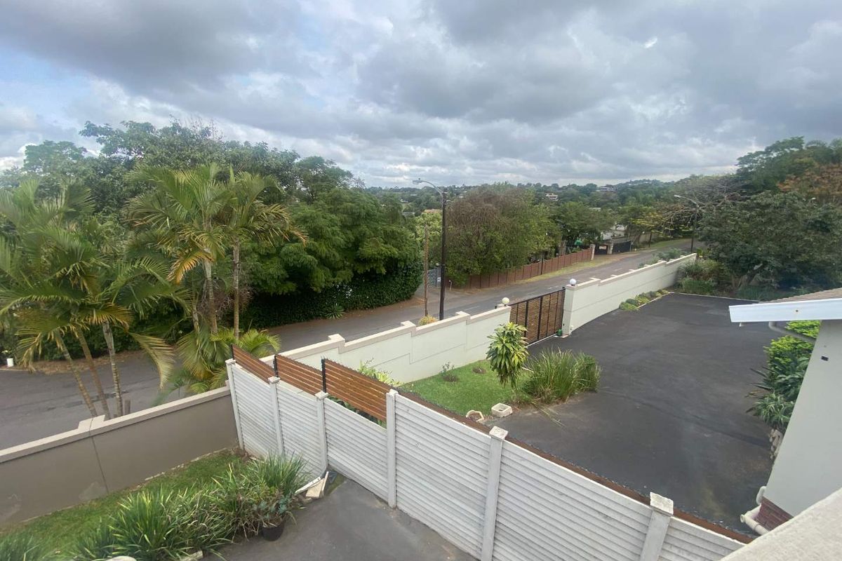 An elevated view of the property driveway, perimeter wall, and surrounding neighborhood landscape.