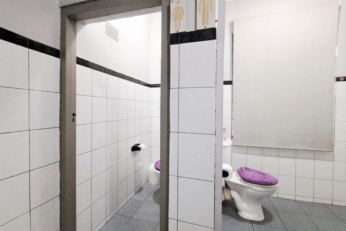 Functional commercial bathroom facility featuring tiled walls and floors with separate toilet cubicle access.