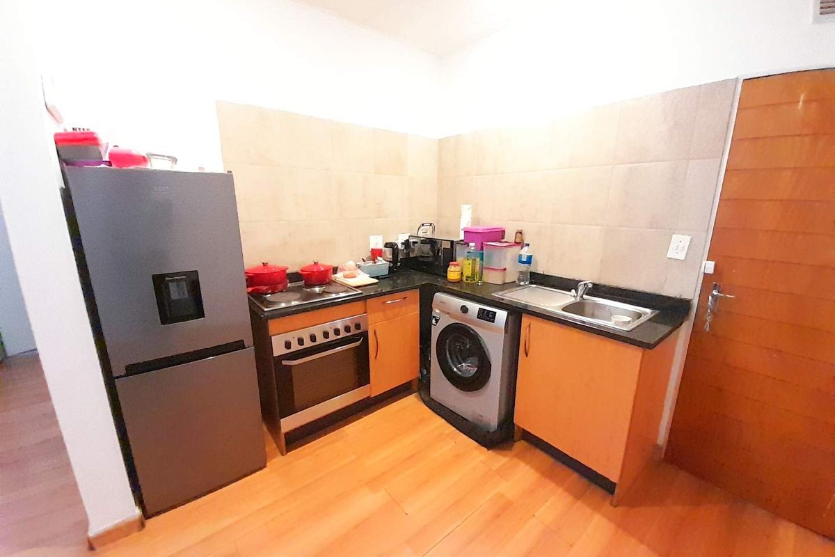 Compact kitchen featuring wooden cabinetry, laminate countertops, tiled backsplash, and integrated cooking appliances, providing a functional workspace.