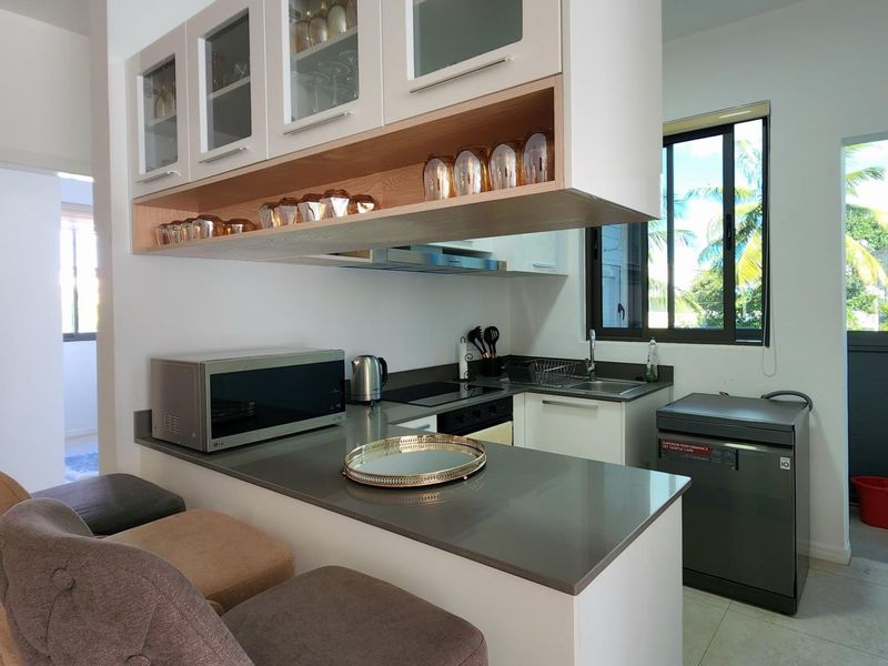 Modern kitchen featuring sleek quartz countertops, ample built-in cabinetry, integrated appliances, and a breakfast bar area with natural light.