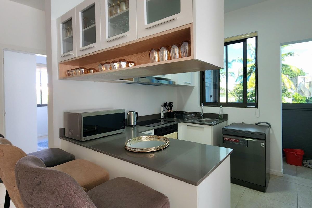 Modern kitchen featuring sleek quartz countertops, ample built-in cabinetry, integrated appliances, and a breakfast bar area with natural light.