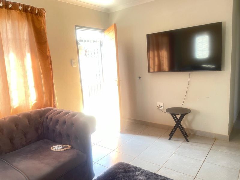 A living room area featuring tiled flooring and direct access to an exterior security gate.