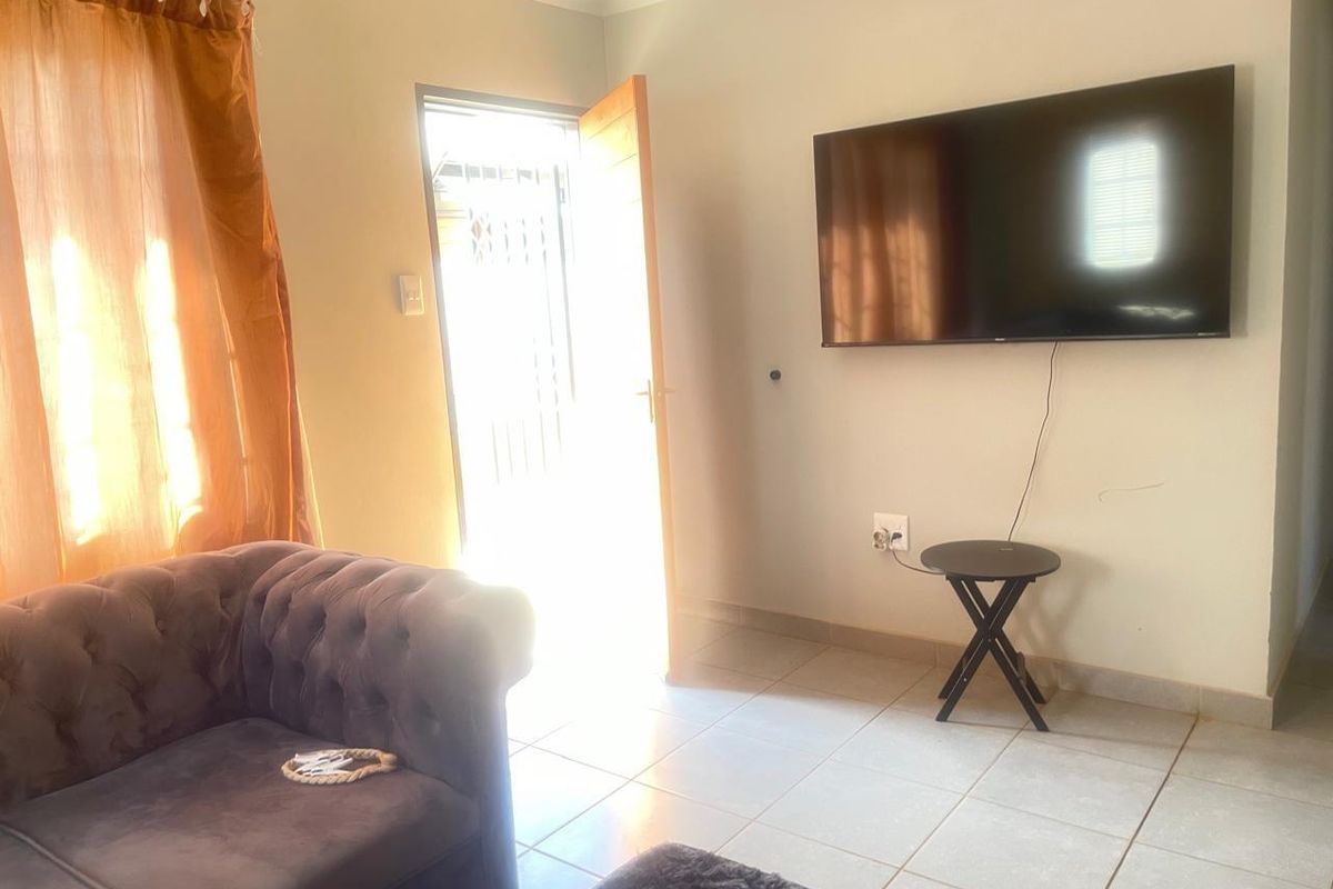 A living room area featuring tiled flooring and direct access to an exterior security gate.