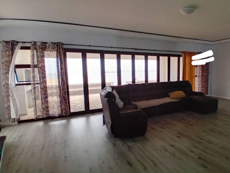Spacious living room featuring modern laminate flooring and expansive folding glass doors that provide ample natural light and access to the outdoors.