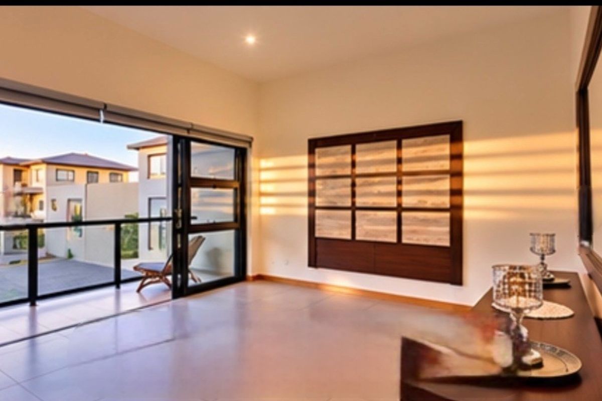 Spacious living area featuring large sliding glass doors opening onto a balcony, complemented by modern tiled flooring and integrated wall cabinetry.