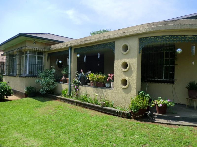 Rear view of the house featuring a covered patio area with decorative circular wall cutouts, security bars, and a well-maintained lawn.