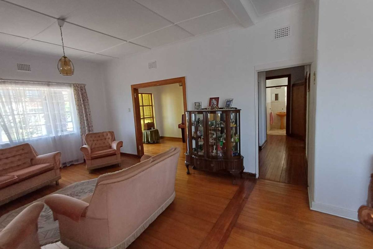 Spacious living area featuring original timber flooring, high ceilings, and seamless flow into adjacent rooms and hallway.