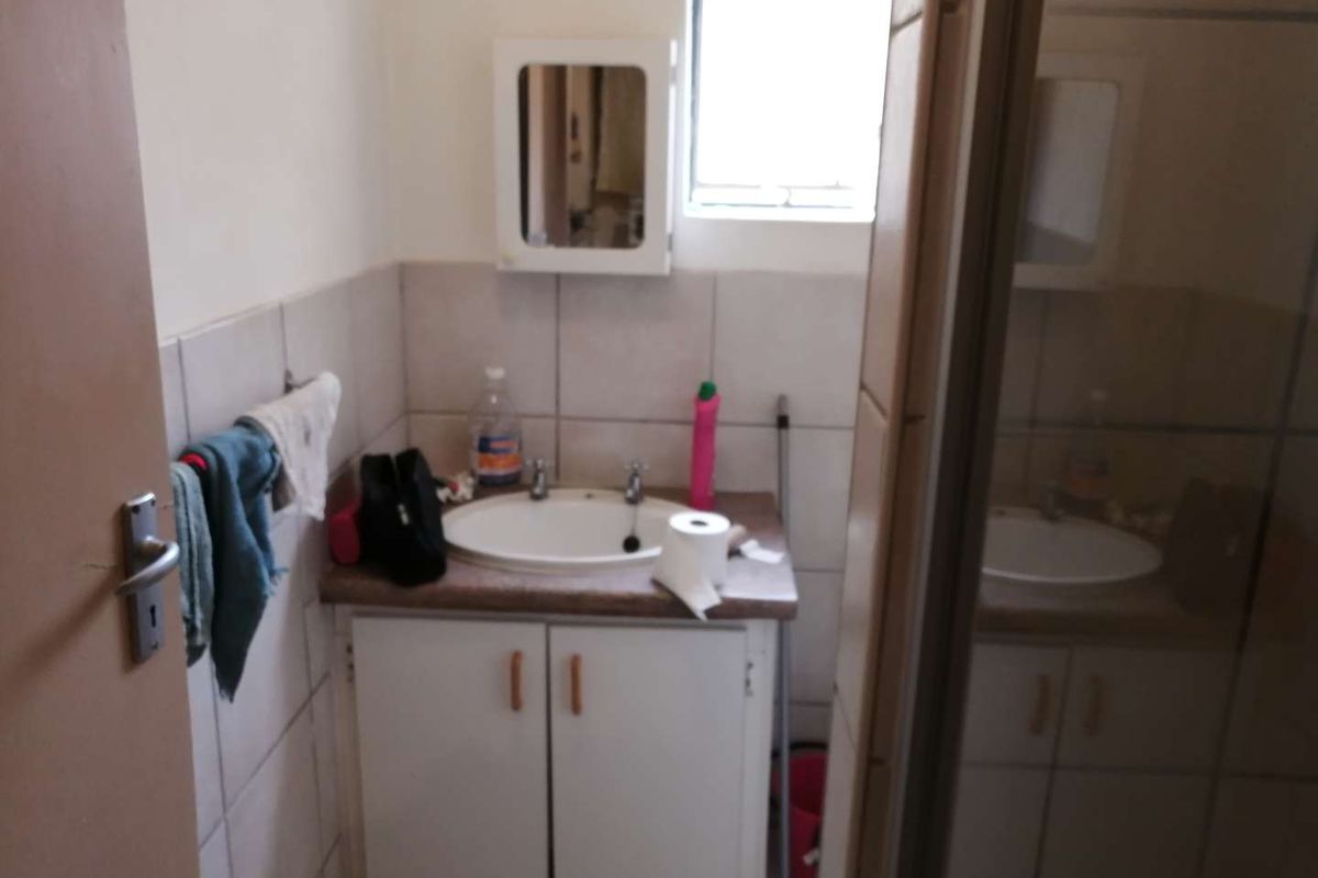 A compact bathroom featuring a vanity cabinet with a basin, tiled walls, and a wall-mounted medicine cabinet.