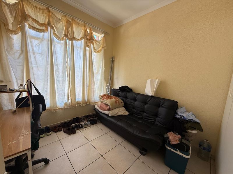 A bedroom featuring tiled flooring and a large window, providing natural light to the space.