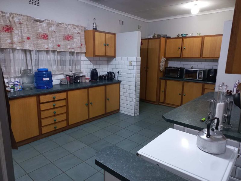 A functional kitchen featuring wooden cabinetry, subway tile backsplash, laminate countertops, and tiled flooring, offering a classic layout with ample storage space.