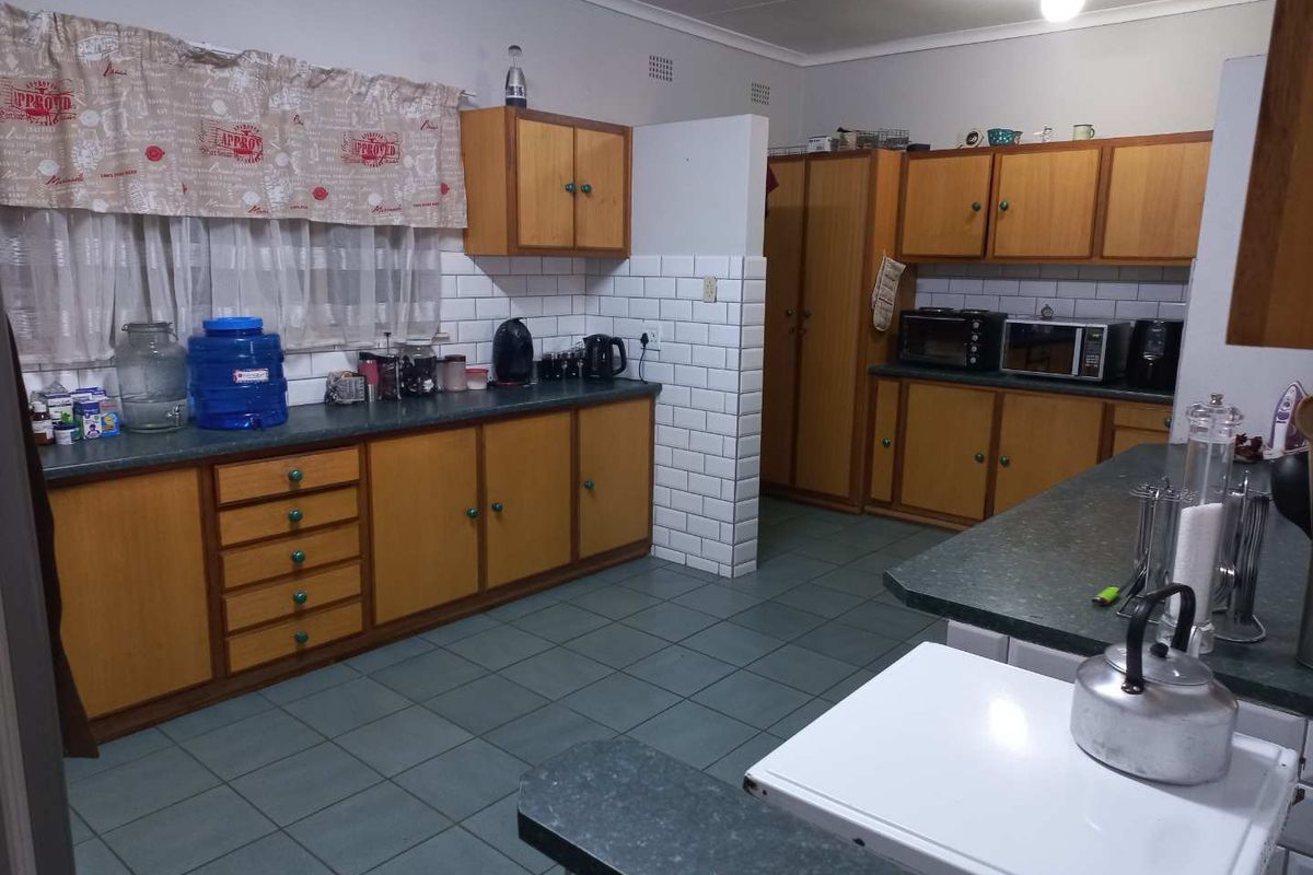 A functional kitchen featuring wooden cabinetry, subway tile backsplash, laminate countertops, and tiled flooring, offering a classic layout with ample storage space.
