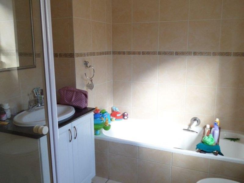A functional bathroom featuring a built-in vanity with sink, a bathtub, a separate shower enclosure, and neutral wall and floor tiling.