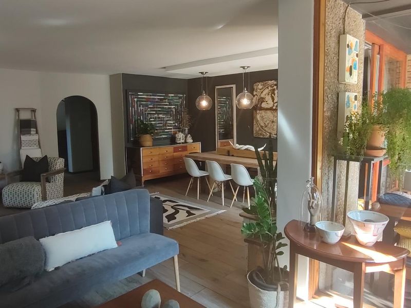 Spacious open-plan living and dining area featuring hardwood flooring, an exposed brick feature wall, and large sliding glass doors leading to the patio.