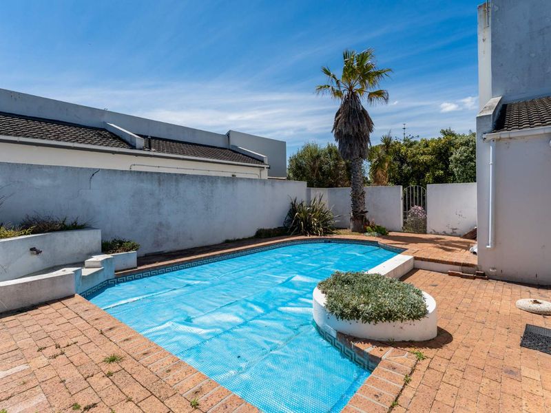 Outdoor pool area featuring brick paving, a built-in planter, and a boundary wall, providing a private space for relaxation and recreation.