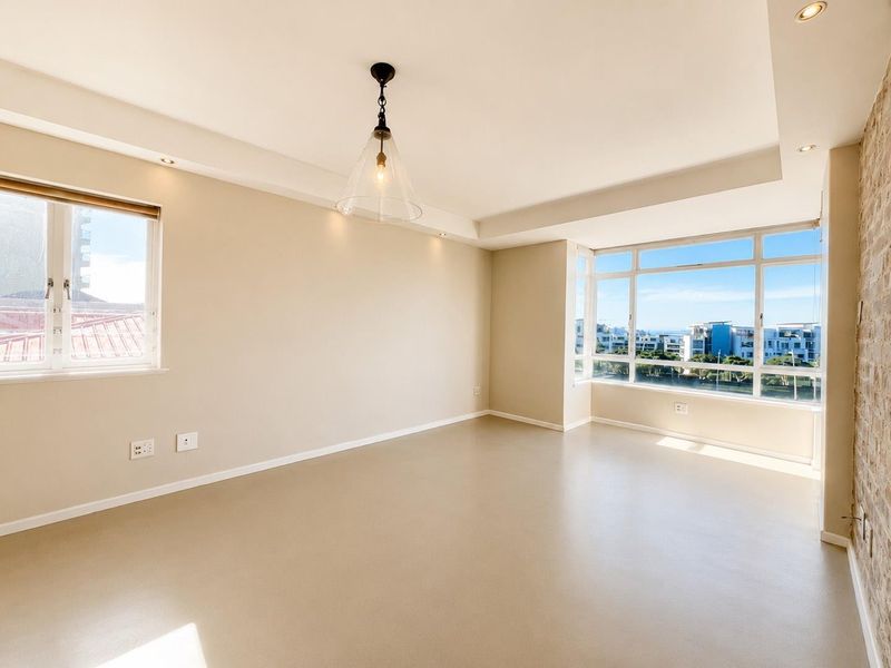 Bright and spacious living area featuring smooth screed flooring, an exposed brick accent wall, and large windows offering expansive views.