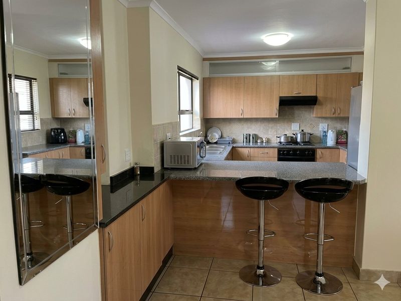 Functional kitchen featuring laminate cabinetry, granite countertops, a breakfast bar, and tiled flooring, offering a practical layout for daily cooking and dining.