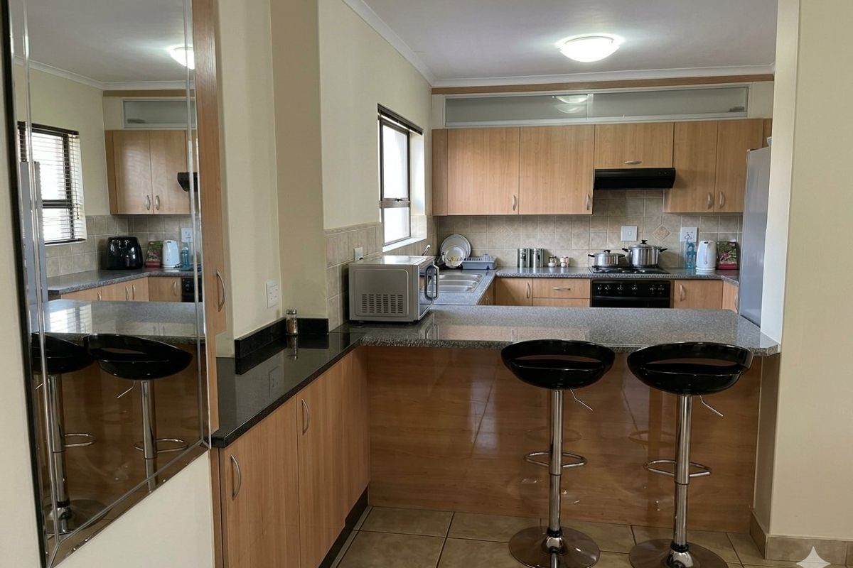 Functional kitchen featuring laminate cabinetry, granite countertops, a breakfast bar, and tiled flooring, offering a practical layout for daily cooking and dining.