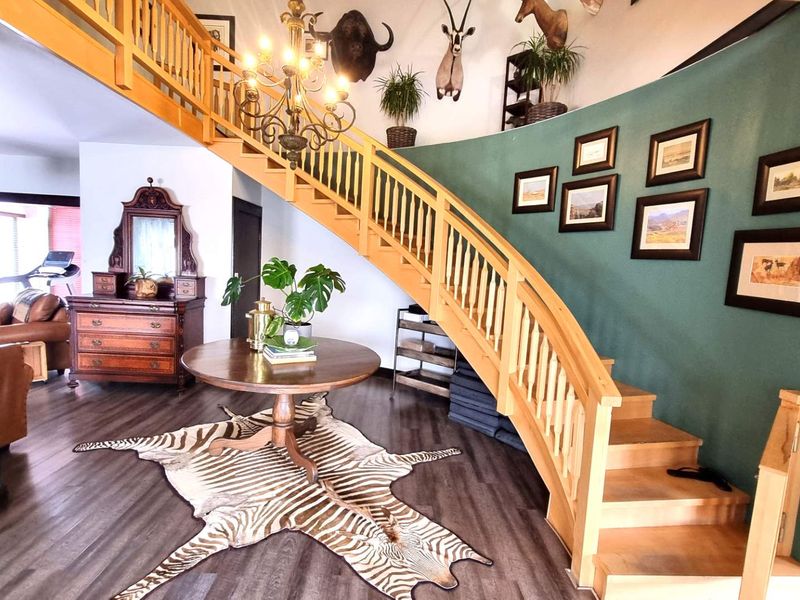 Spacious entrance hall featuring a prominent curved wooden staircase with a matching balustrade and modern laminate flooring.