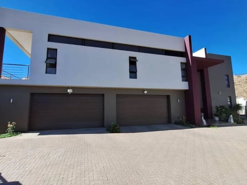 Modern double-story residential property featuring a paved driveway, double garage, and an upper-level balcony with contemporary architectural finishes.