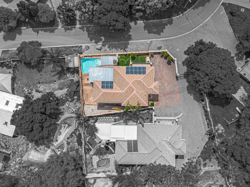Aerial view of the property showcasing the main house, swimming pool, solar panel installation, and surrounding landscaped grounds.