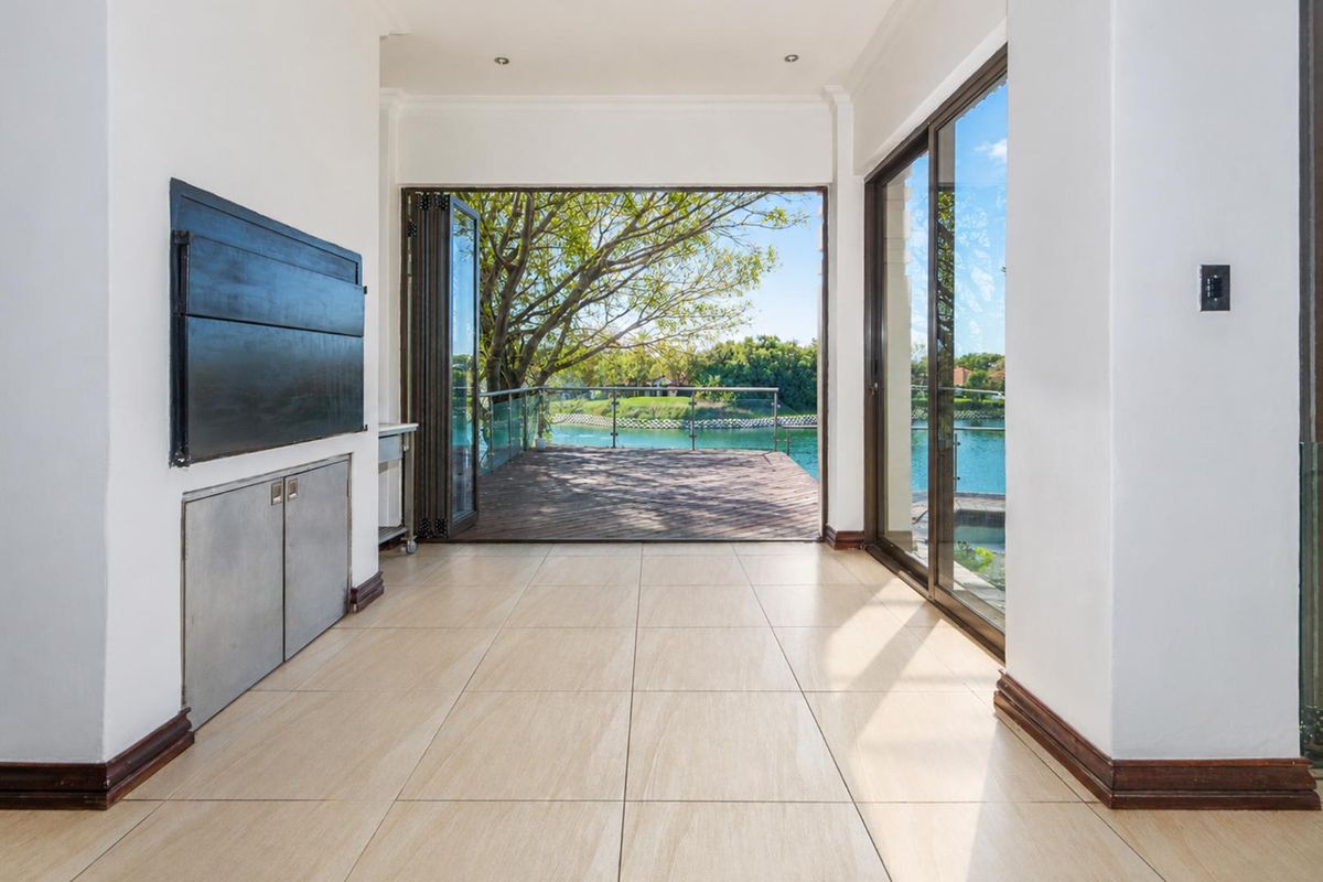 Bright living area featuring large bi-fold doors opening onto a wooden deck with scenic water views.