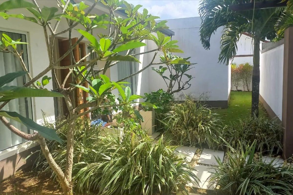 A private rear garden area featuring landscaped greenery, paved stepping stones, and direct access to the home through sliding glass doors.