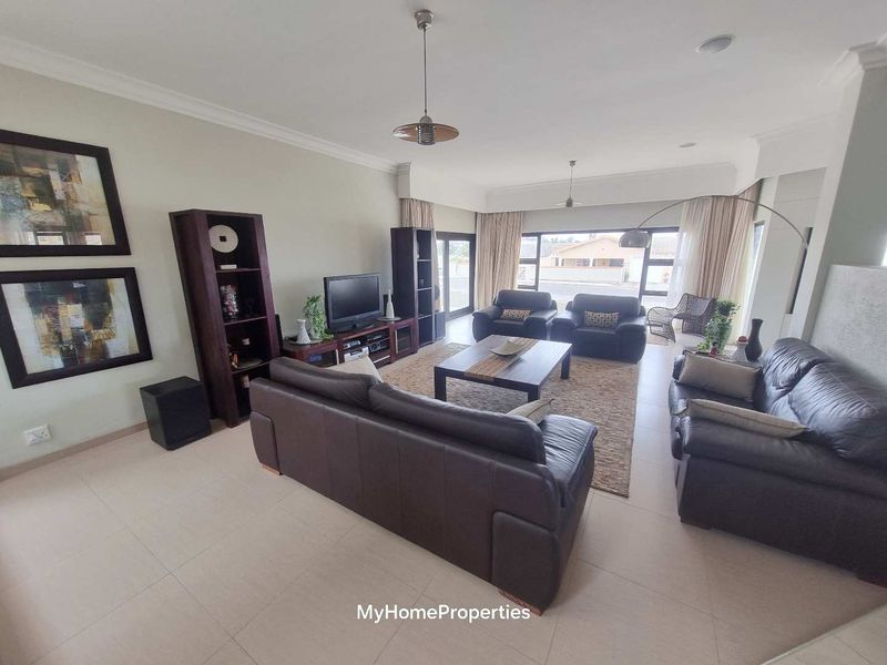 Spacious living room featuring neutral tiled flooring, recessed lighting, and large sliding glass doors providing ample natural light.