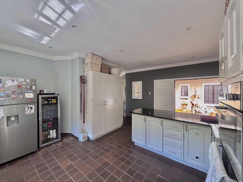 A functional kitchen featuring tiled flooring, granite countertops, built-in cabinetry, and recessed lighting, with a convenient pass-through window to the outdoor area.