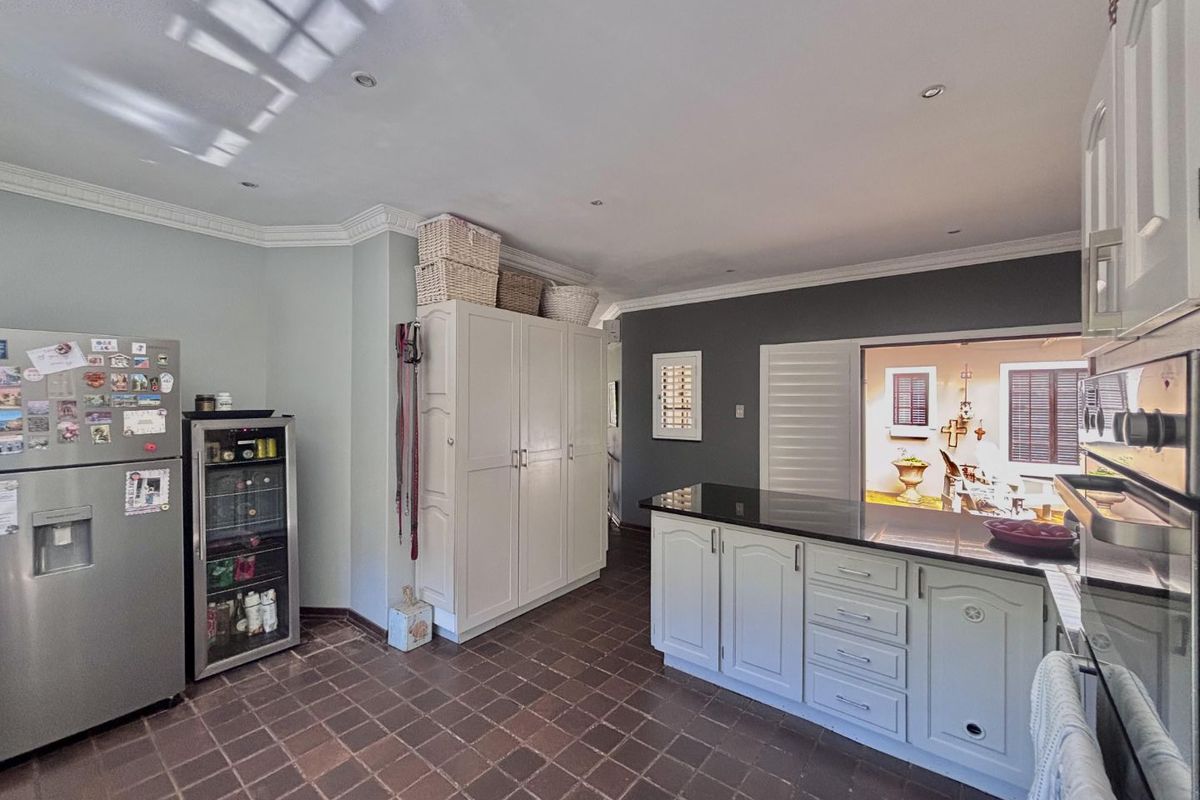 A functional kitchen featuring tiled flooring, granite countertops, built-in cabinetry, and recessed lighting, with a convenient pass-through window to the outdoor area.