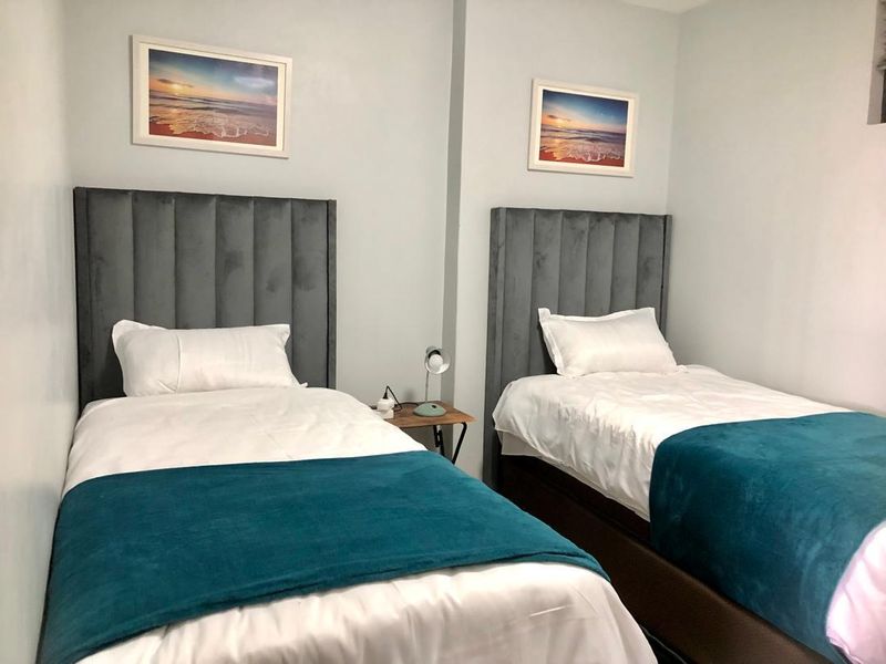 A well-maintained bedroom featuring two twin beds with upholstered headboards and neutral wall finishes.