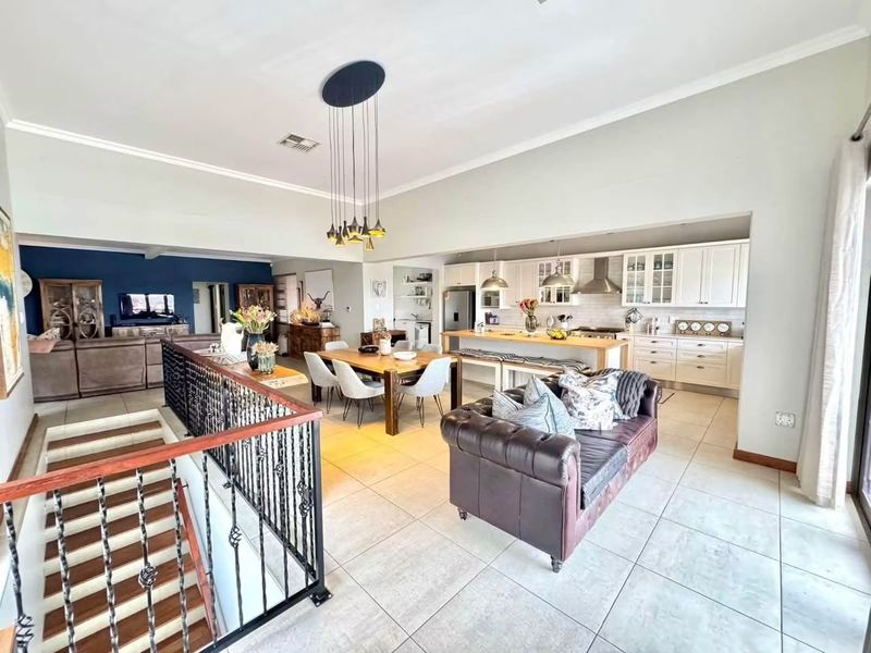 Spacious open-plan living area featuring a modern kitchen with island, dining space, and a staircase with decorative wrought iron railing.