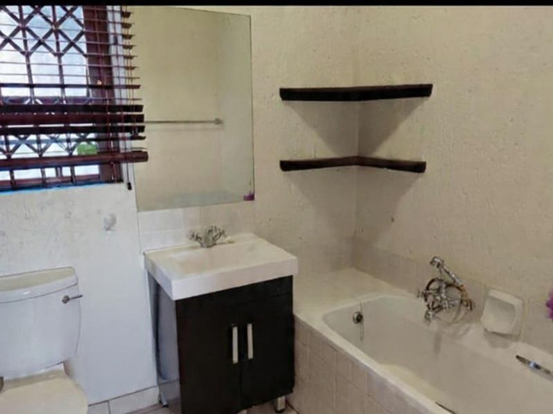 A dated bathroom featuring a vanity cabinet, bathtub, and toilet, requiring cosmetic updates to improve the overall aesthetic and condition.