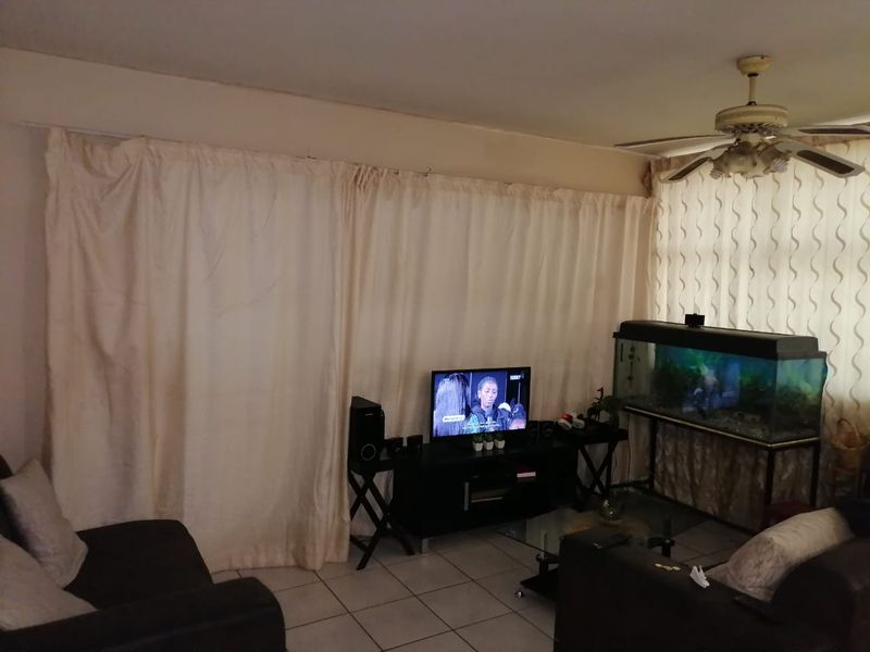 A living room area featuring tiled flooring and a ceiling fan, providing a functional space for relaxation.