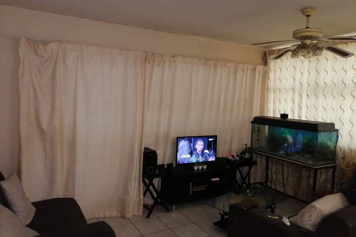 A living room area featuring tiled flooring and a ceiling fan, providing a functional space for relaxation.