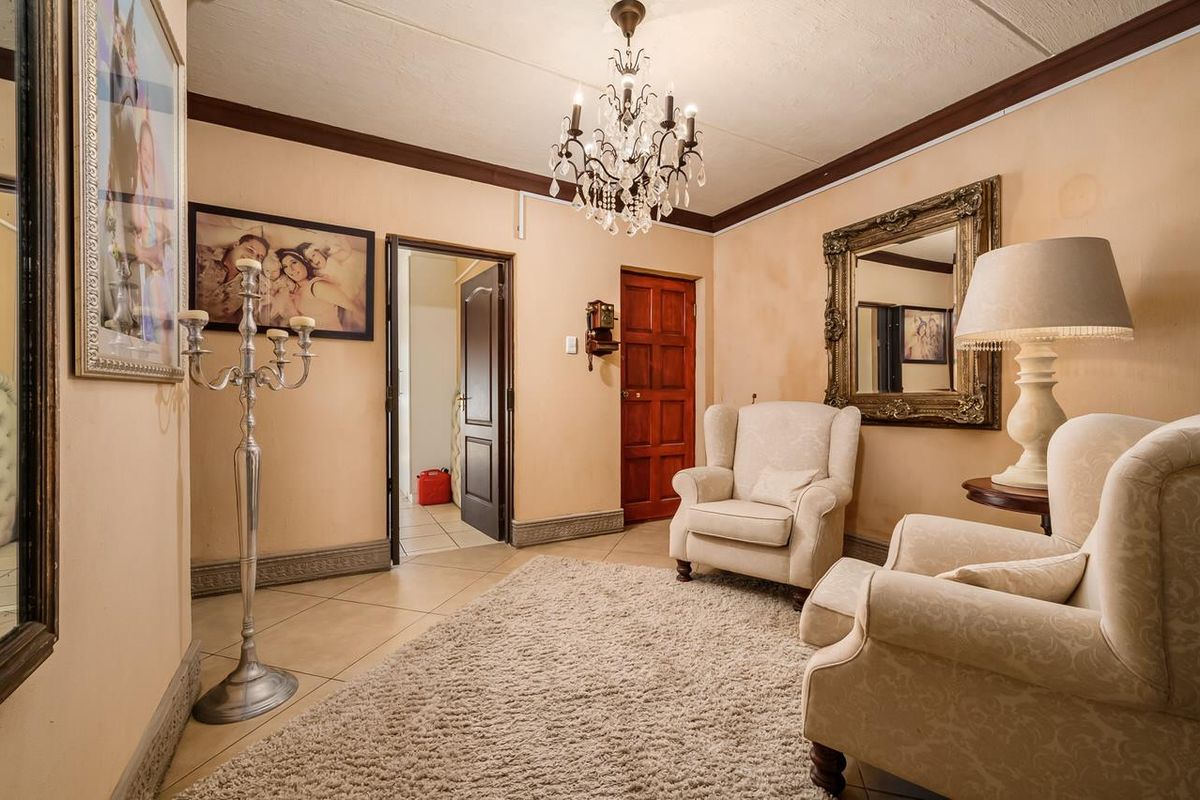 A formal living area featuring tiled flooring, a decorative chandelier, and traditional wooden door finishes.