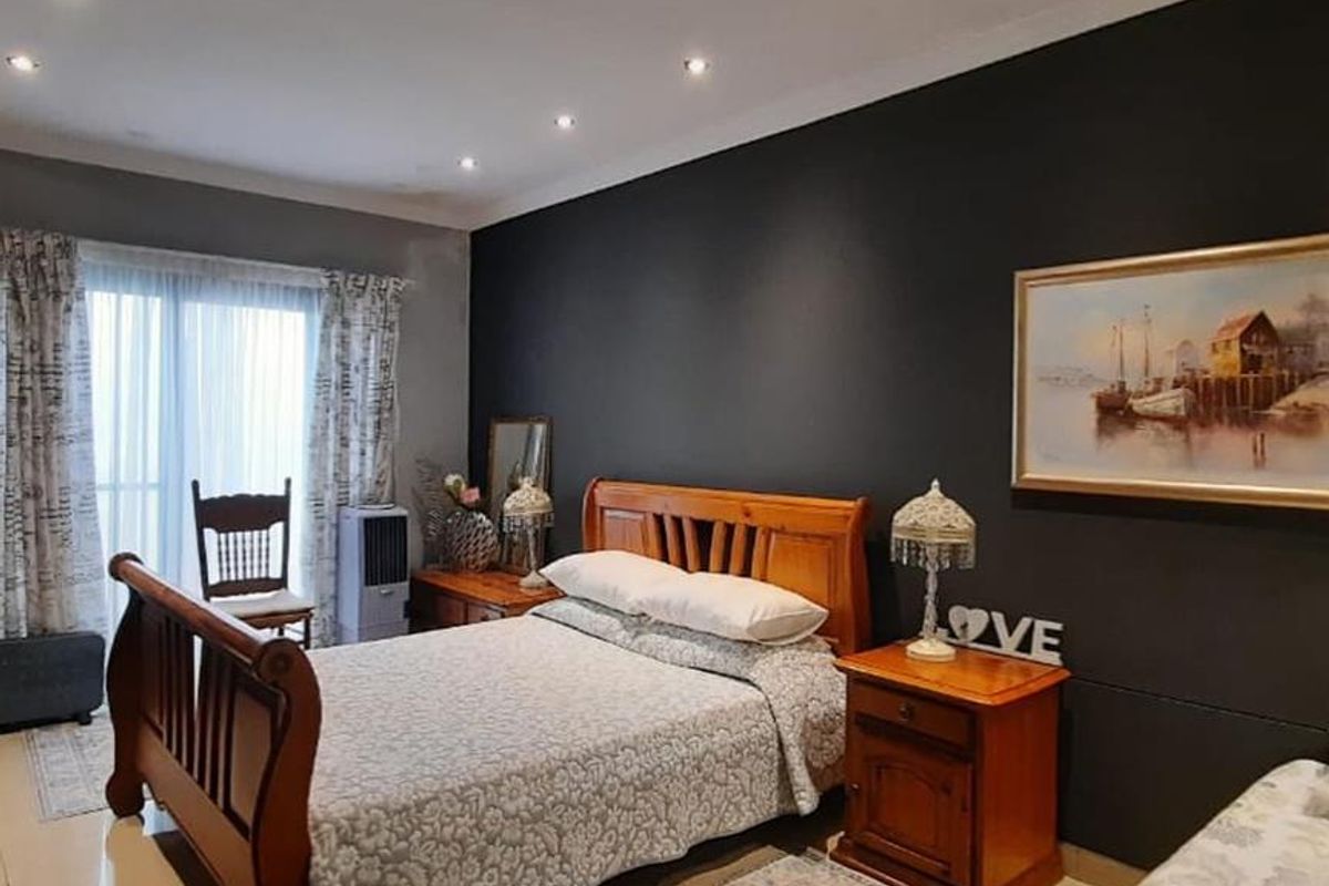A spacious bedroom featuring tiled flooring, recessed ceiling lighting, and a large sliding glass door providing access to the exterior.