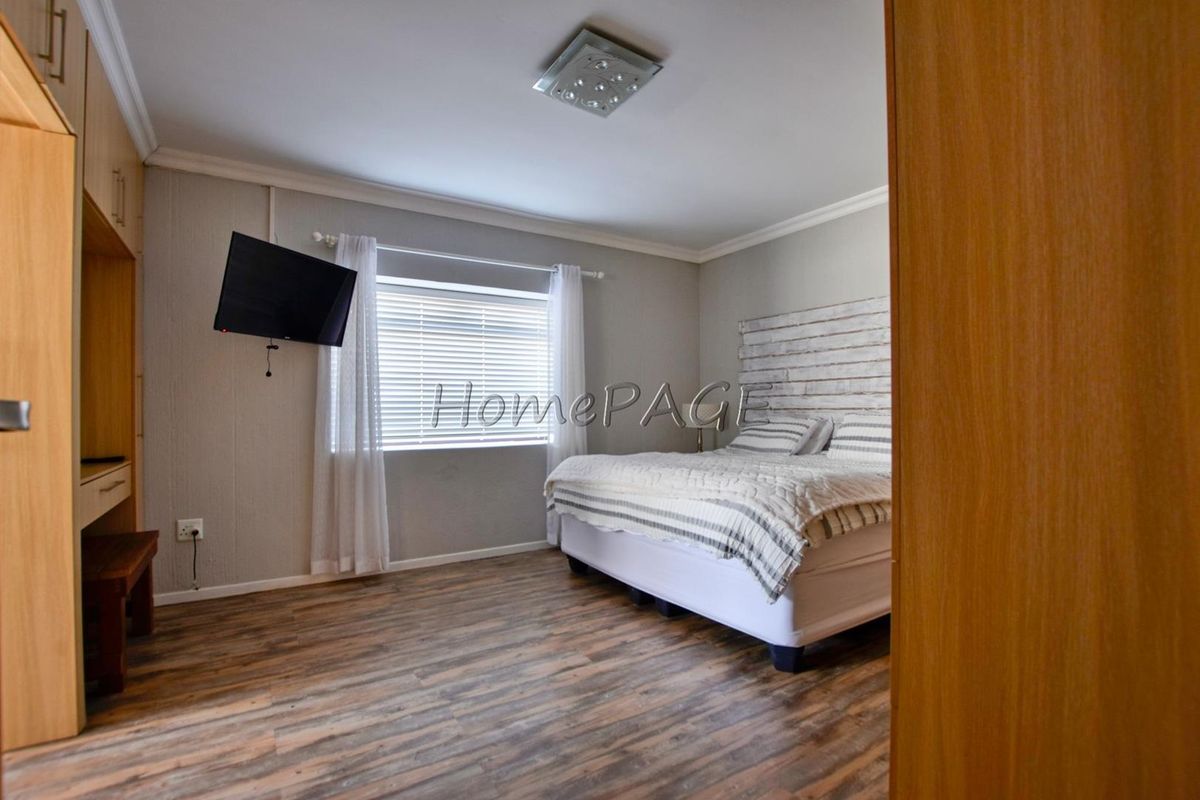 A well-maintained bedroom featuring wood-look laminate flooring, built-in cabinetry, and a window with fitted blinds.