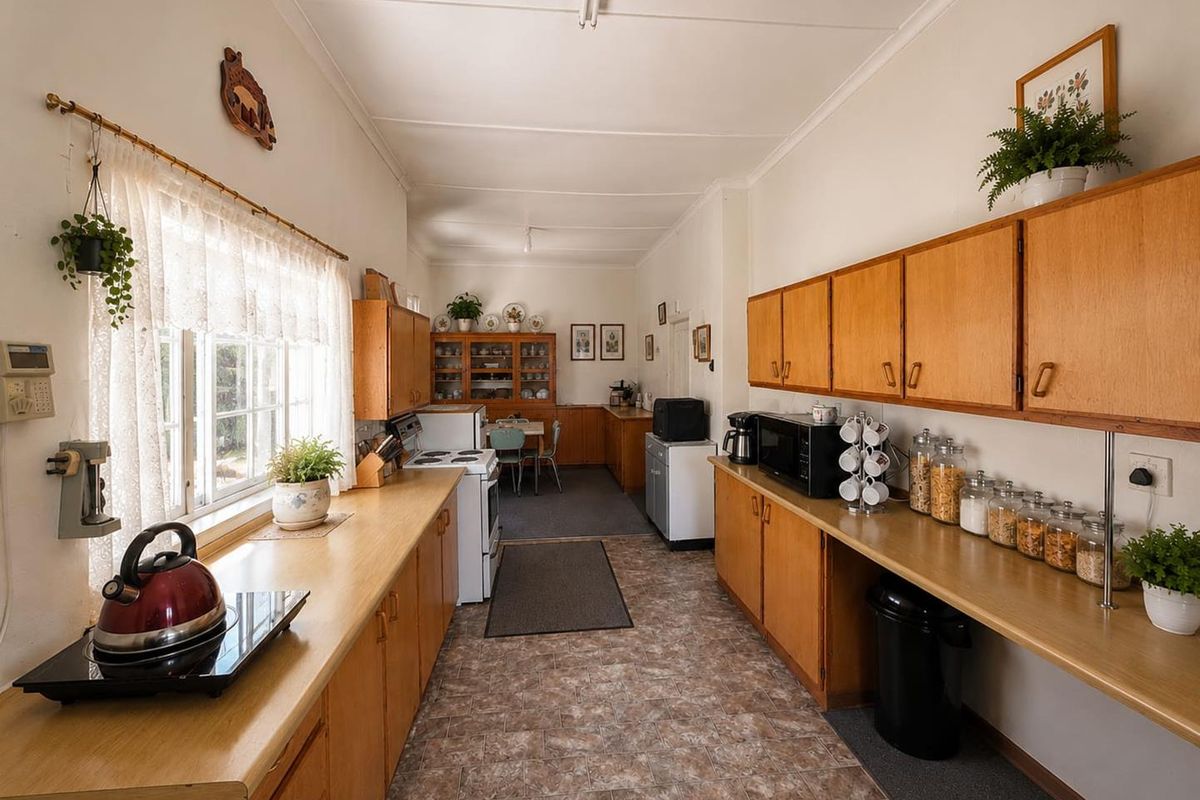 A functional, galley-style kitchen featuring extensive wooden cabinetry, laminate countertops, and a freestanding stove, offering a classic layout with potential for modern updates.