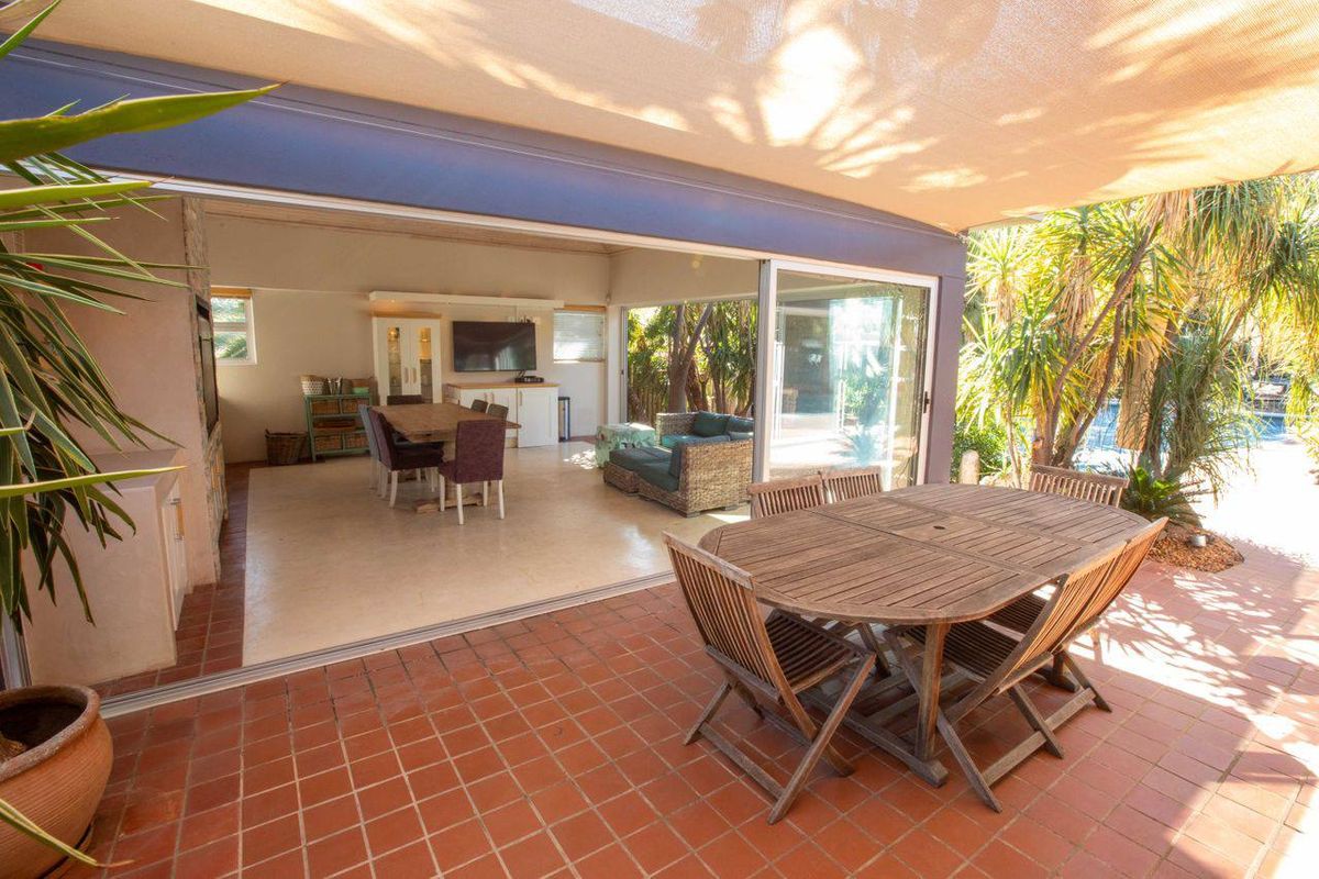 Spacious covered patio featuring terracotta tiling and a built-in fireplace, seamlessly connecting to the indoor living area through large sliding glass doors.