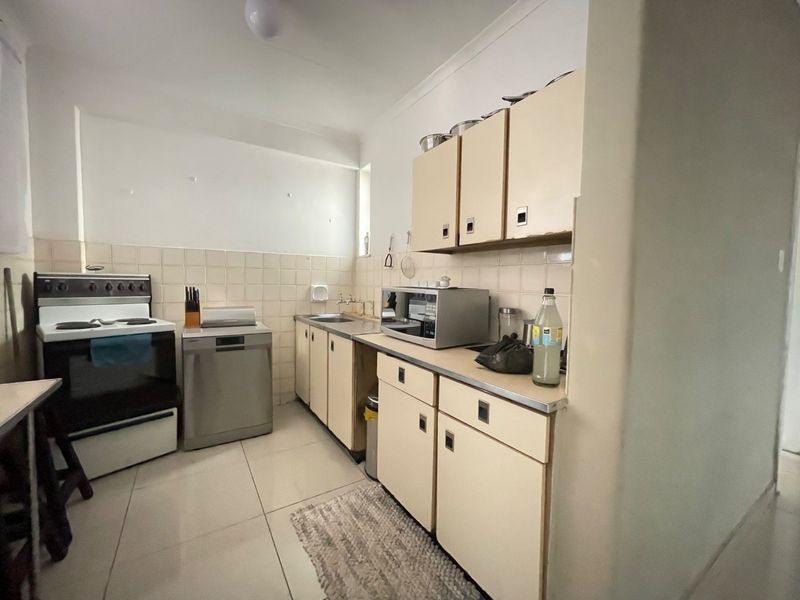 A functional kitchen featuring tiled flooring, a tiled backsplash, built-in cabinetry, and integrated appliances, offering a practical layout with potential for modern updates.