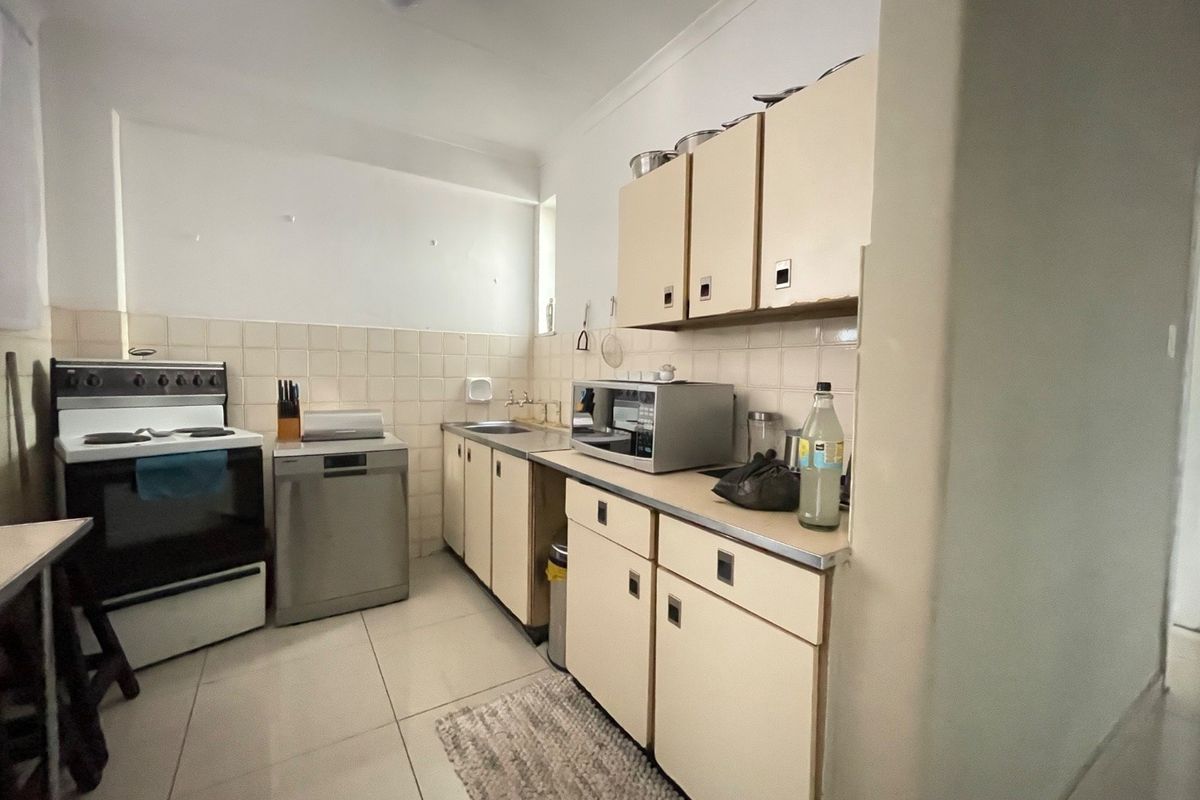 A functional kitchen featuring tiled flooring, a tiled backsplash, built-in cabinetry, and integrated appliances, offering a practical layout with potential for modern updates.
