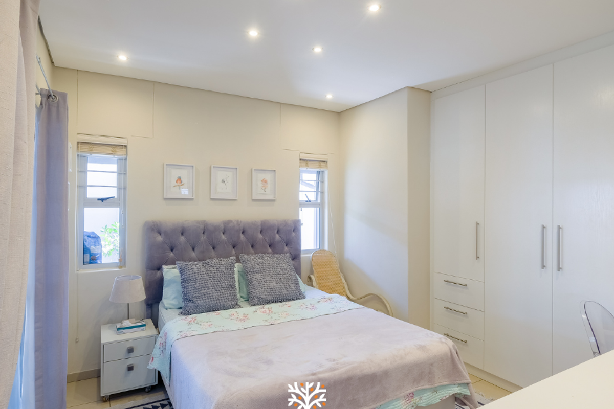 A well-maintained bedroom featuring built-in floor-to-ceiling wardrobes, recessed ceiling lighting, and tiled flooring.