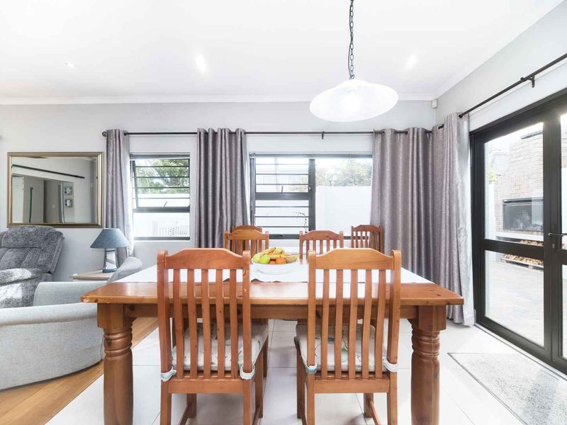Bright open-plan living and dining area featuring tiled floors, recessed lighting, and large aluminium sliding doors providing direct access to the outdoor patio.
