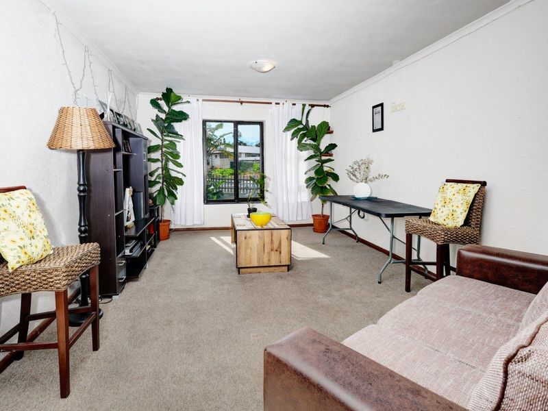 A living room featuring carpeted flooring and a window, providing a functional space with neutral wall finishes.