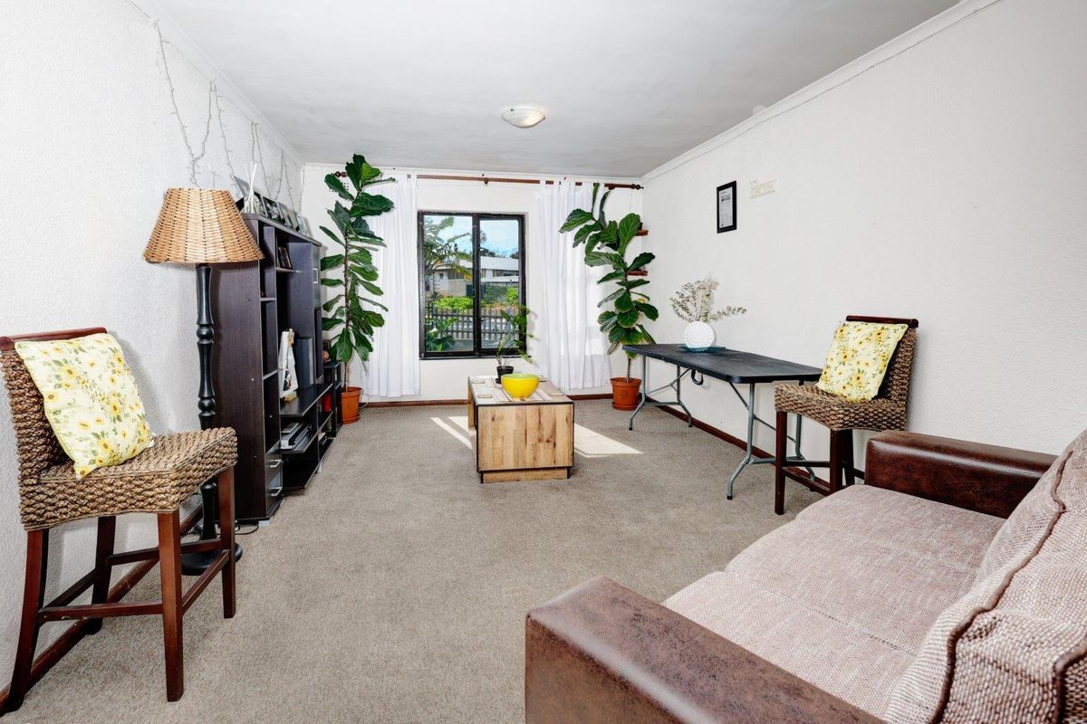 A living room featuring carpeted flooring and a window, providing a functional space with neutral wall finishes.