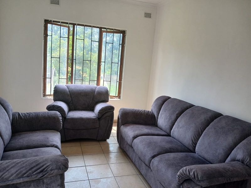 A living room featuring tiled flooring, large windows with security bars, and neutral walls, offering a functional space with potential for modernization.