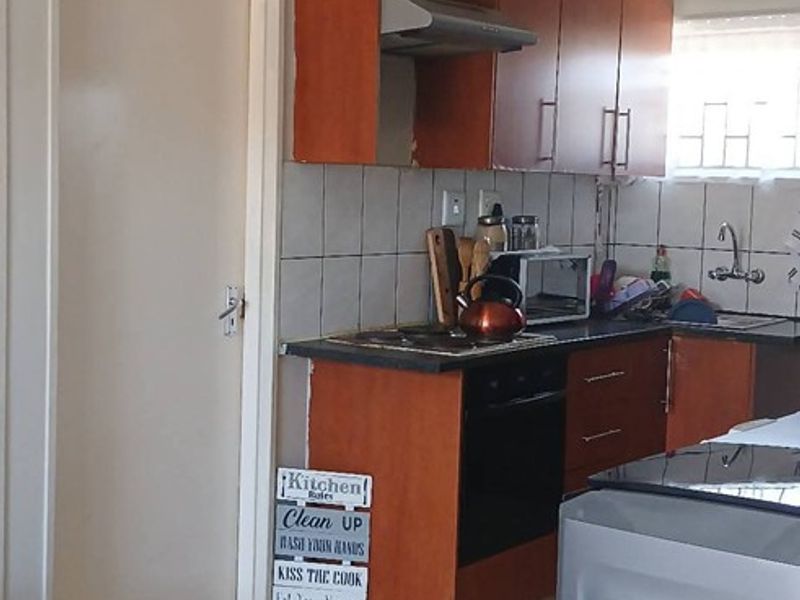 A functional kitchen featuring wooden cabinetry, a built-in oven with extractor fan, tiled backsplash, and tiled flooring.