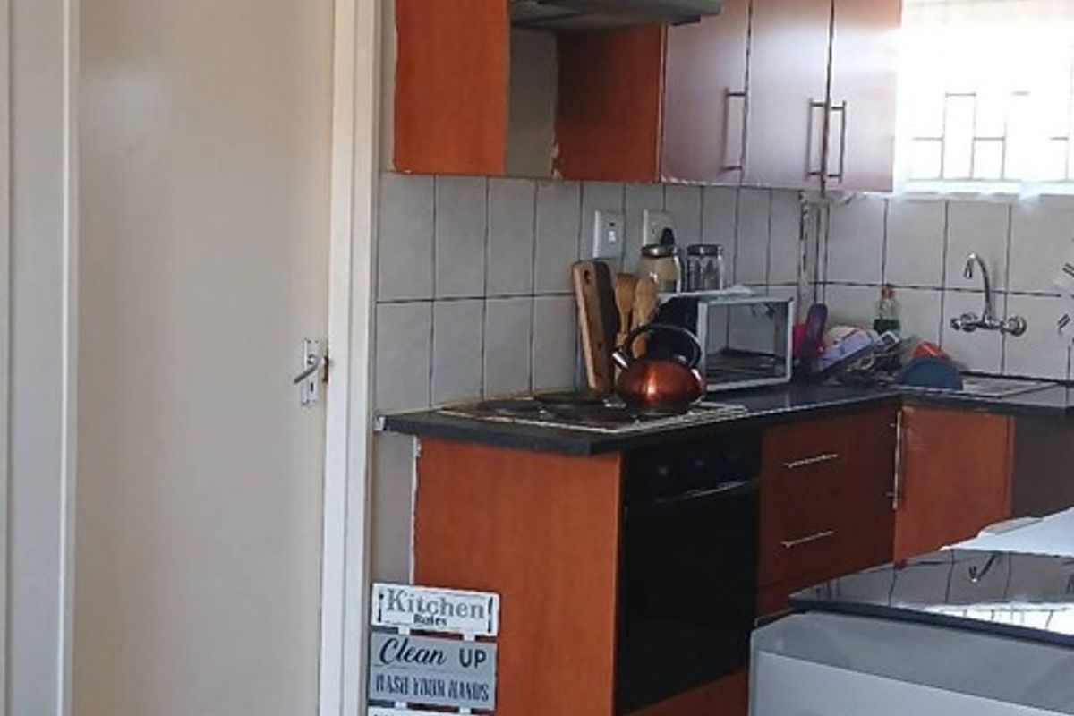 A functional kitchen featuring wooden cabinetry, a built-in oven with extractor fan, tiled backsplash, and tiled flooring.