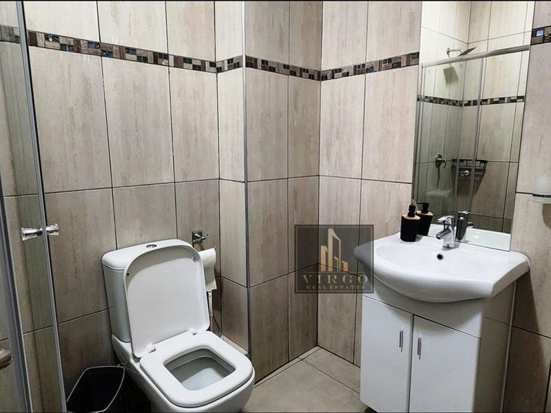 A clean, modern bathroom featuring tiled walls, a vanity cabinet with a washbasin, and a glass-enclosed shower.