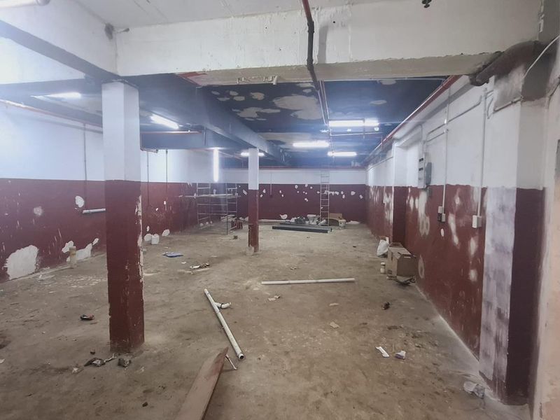 An expansive, open-plan industrial utility space featuring exposed ceilings, fire sprinkler infrastructure, and structural columns, currently in need of renovation and finishing.